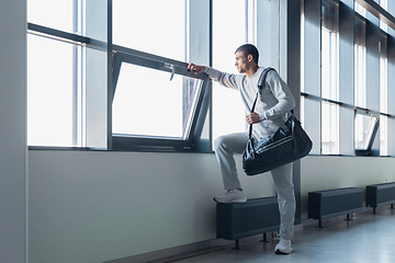 Image showing Sports man against modern glassed building, airport in megapolis