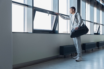 Image showing Sports man against modern glassed building, airport in megapolis