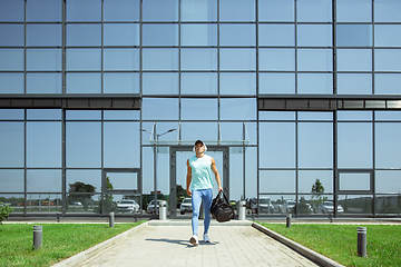 Image showing Sports man against modern glassed building, airport in megapolis