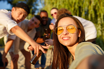 Image showing Group of friends clinking beer glasses during picnic at the beach. Lifestyle, friendship, having fun, weekend and resting concept.