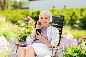 Image showing old woman with headphones and smartphone at garden