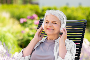 Image showing happy senior woman with headphones at garden