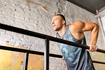 Image showing man doing triceps dip on parallel bars in gym