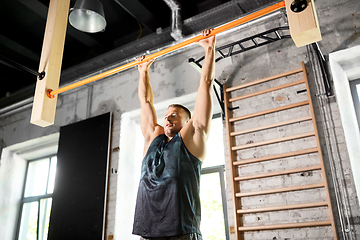 Image showing man exercising on bar and doing pull-ups in gym