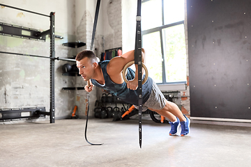 Image showing man doing push-ups on gymnastic rings in gym