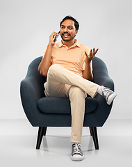 Image showing happy indian man calling on smartphone in chair
