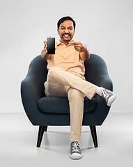 Image showing happy young indian man showing smartphone in chair