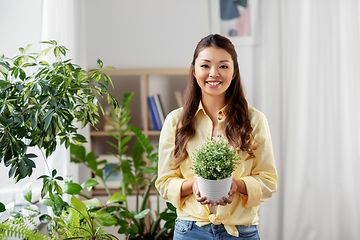 Image showing happy asian woman with flower in pot at home