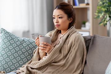 Image showing sad sick asian woman drinking hot tea at home