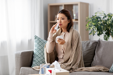 Image showing sick asian woman with nasal spray medicine at home