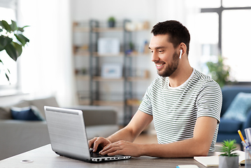 Image showing man with laptop and earphones at home office