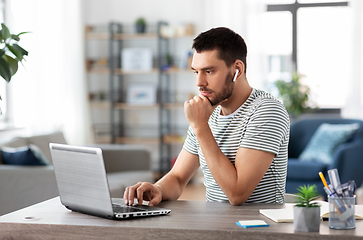 Image showing man with laptop and earphones at home office