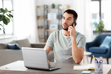 Image showing man with laptop calling on phone at home office