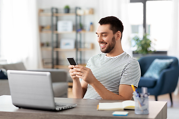 Image showing man with smartphone and laptop at home office