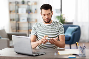 Image showing man using hand sanitizer at home office