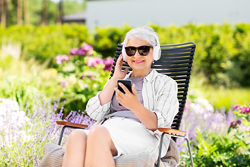 Image showing old woman with headphones and smartphone at garden