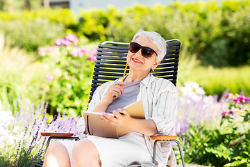 Image showing happy senior woman with diary at summer garden