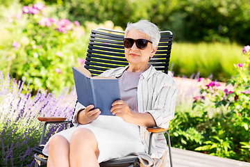 Image showing happy senior woman reading book at summer garden