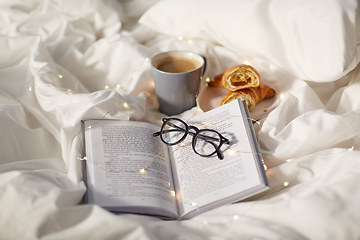 Image showing croissants, cup of coffee, book and glasses in bed