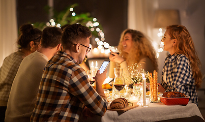 Image showing man with smartphone at dinner party with friends