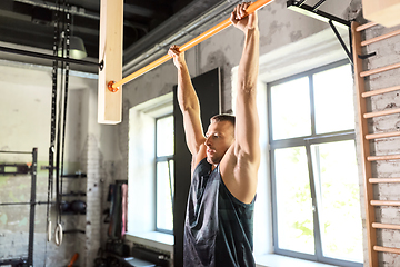 Image showing man exercising on bar and doing pull-ups in gym