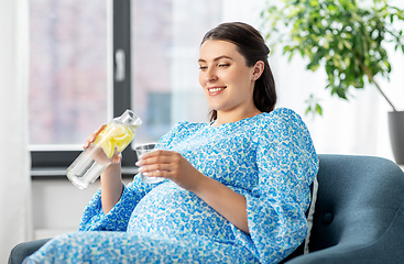 Image showing happy pregnant woman drinking fruit water at home