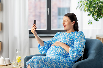 Image showing happy pregnant woman with smartphone at home