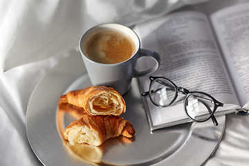 Image showing croissants, cup of coffee and book in bed at home