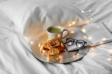 Image showing croissants, matcha tea, book and glasses in bed