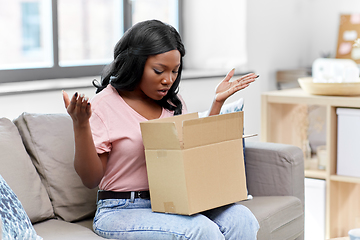 Image showing sad african american woman with parcel box at home