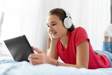 Image showing girl in headphones listening to music on tablet pc