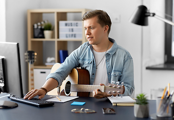 Image showing young man with guitar and computer at home