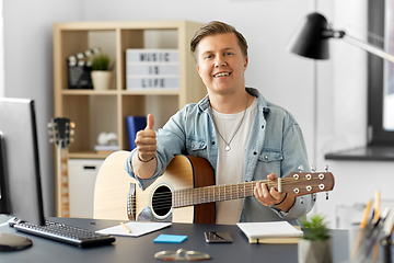 Image showing happy man with guitar showing thumbs up at home