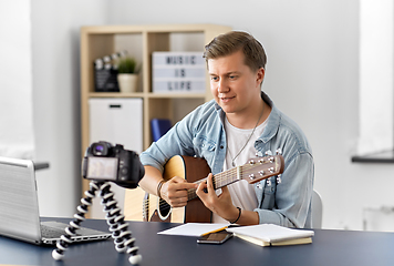 Image showing man or blogger with camera playing guitar at home