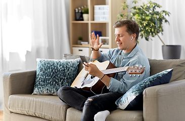 Image showing man with guitar, earphones and smartphone at home