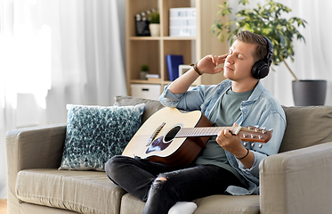 Image showing man in headphones playing guitar at home