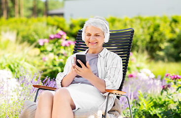 Image showing old woman with headphones and smartphone at garden