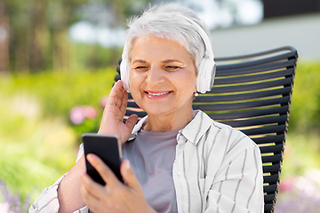 Image showing old woman with headphones and smartphone at garden