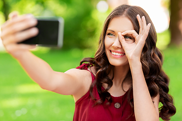 Image showing happy woman with smartphone taking selfie at park