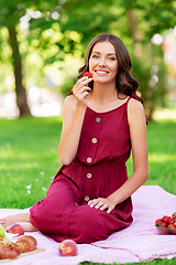 Image showing happy woman eating strawberry on picnic at park