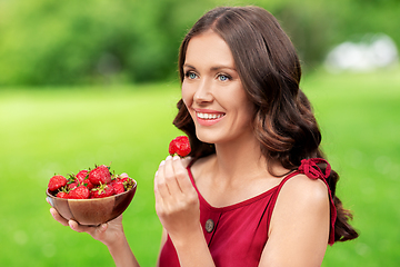 Image showing happy woman eating strawberry at summer park