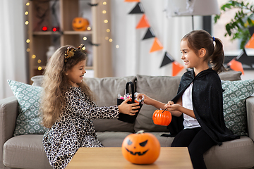 Image showing girls in halloween costumes with candies at home