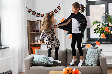 Image showing girls in halloween costumes jumping on sofa