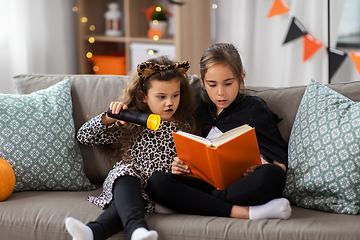 Image showing girls in halloween costumes reading book at home