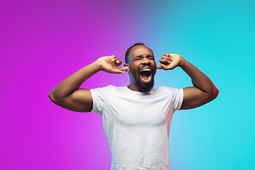 Image showing African-american young man\'s portrait on gradient studio background in neon