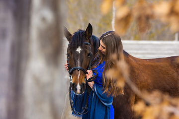 Image showing Touching portrait of a girl in a blue dress with a horse