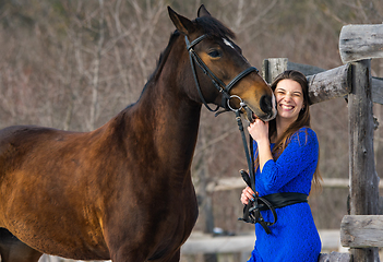 Image showing The horse caresses and bites the hand of a young beautiful girl