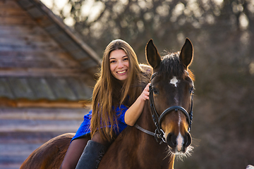 Image showing Girl in a blue dress on a beautiful horse