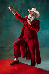 Image showing Modern stylish Santa Claus in red fashionable suit and cowboy\'s hat on dark background