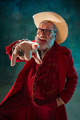 Image showing Modern stylish Santa Claus in red fashionable suit and cowboy\'s hat on dark background